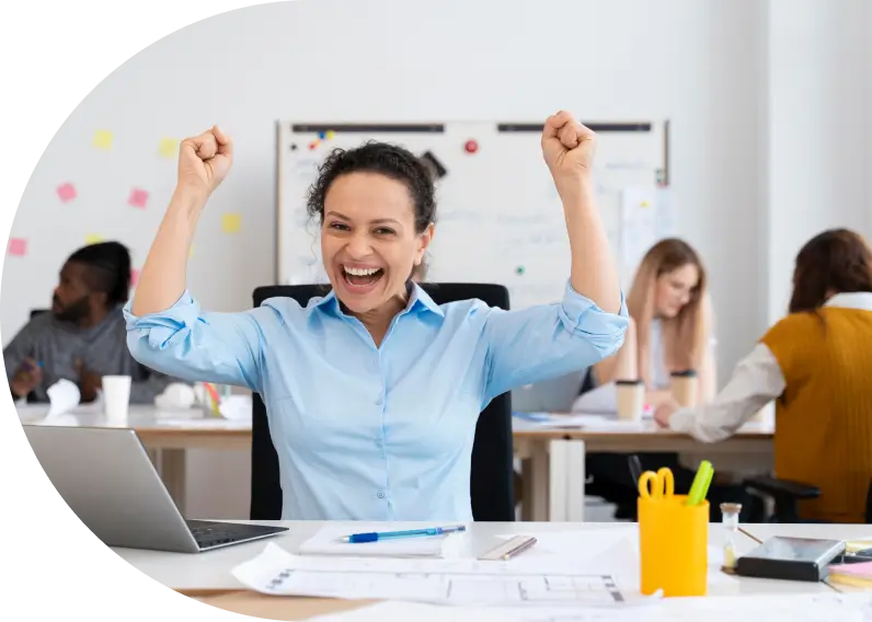 Una mujer de mediana edad celebrando con los brazos en alto en una oficina.